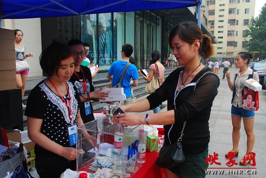 買(mǎi)下義賣(mài)食品的女士將愛(ài)心款投入捐款箱