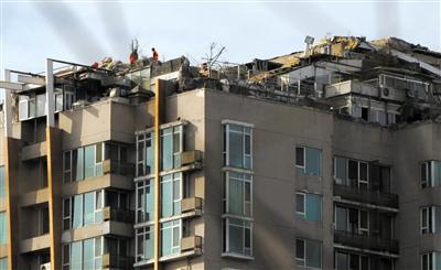 　　昨日，身穿橘黃色馬甲的工作人員在人濟山莊樓頂拆除違章建筑。新京報記者 吳江 攝