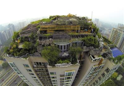 　　昨日，身穿橘黃色馬甲的工作人員在人濟山莊樓頂拆除違章建筑。新京報記者 吳江 攝