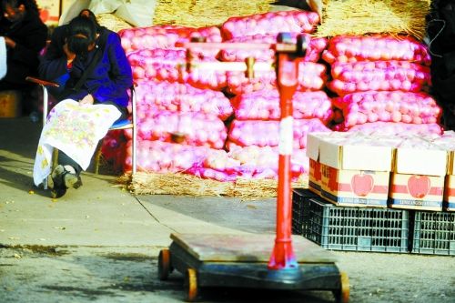 水果批發(fā)市場(chǎng)內(nèi)，沒有客戶時(shí)，商戶在繡十字繡