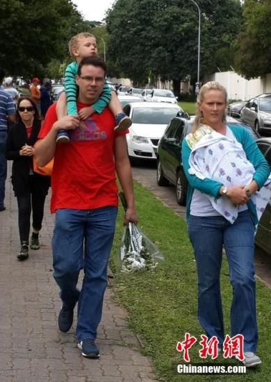 圖為一個(gè)白人家庭，由父母帶著孩子到曼德拉家門外悼念。中新社發(fā) 宋方燦 攝
