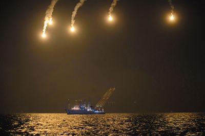 22日，搜救人員在照明彈的光亮下連夜搜救。