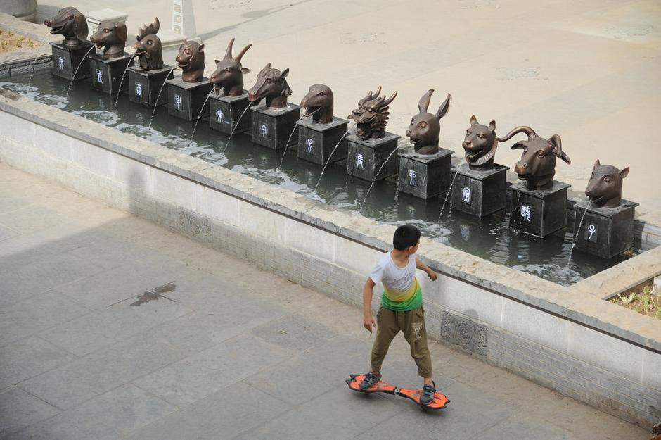 圖為一名市民從獸首旁經(jīng)過。