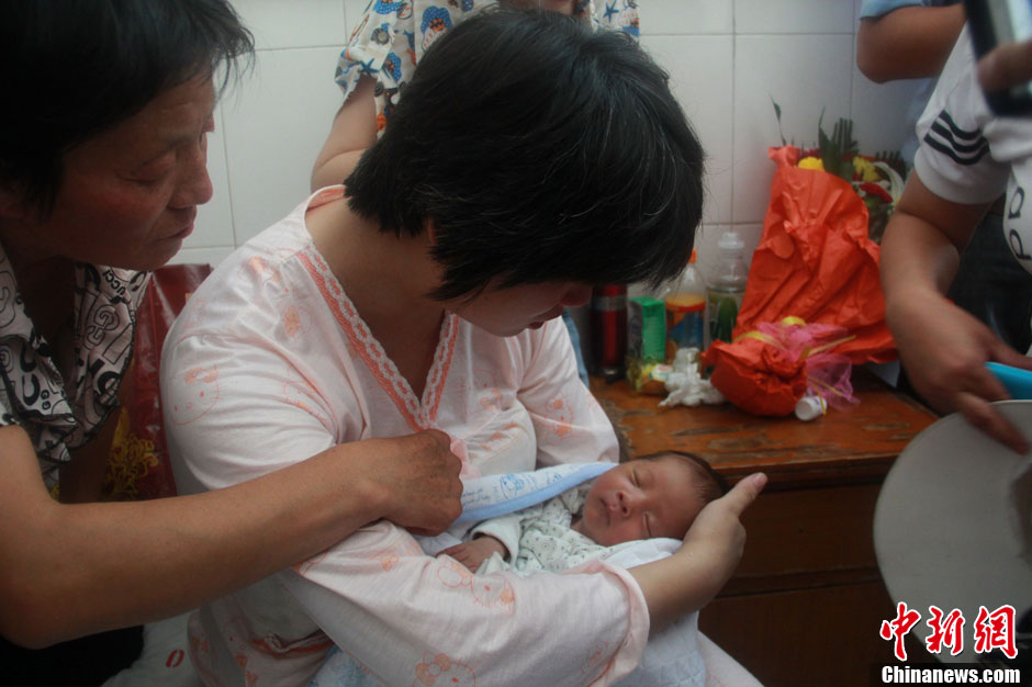 圖為久別重逢，獲救嬰兒母親悉心撫摸愛子。張一辰 攝