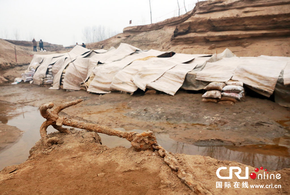 2014年1月6日，河南洛陽古沉船發(fā)掘現(xiàn)場，古沉船鐵錨從見天日，靜靜地躺在古船旁。