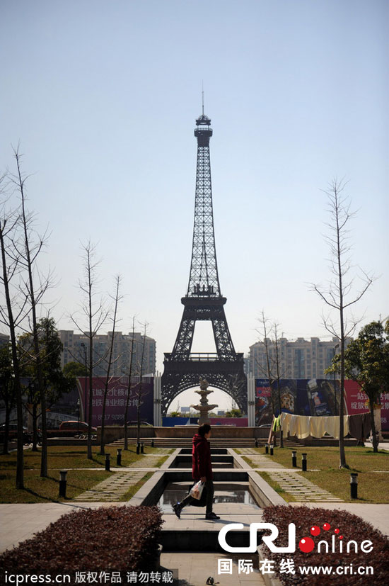 　2014年3月21日，杭州天都城，農(nóng)民在山寨埃菲爾鐵塔下耕作。圖片來源：東方IC