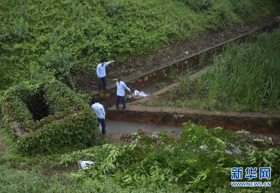 5月18日，工作人員在槽罐車泄漏現(xiàn)場附近的水渠邊查看情況。
