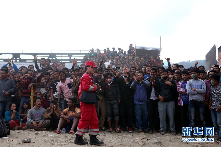 圍觀的尼泊爾民眾在中國(guó)國(guó)際救援隊(duì)成功搜救出幸存者后向搜救隊(duì)員歡呼致意。
