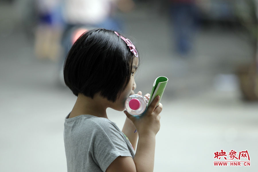 6月7日，鄭州回中考點，一名孩子拿著一瓶礦泉水，等待哥哥走出考場