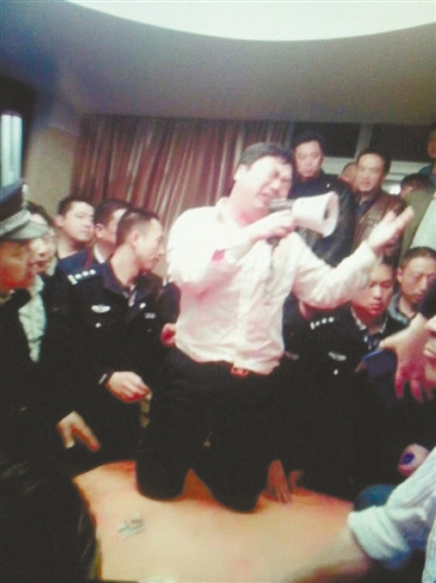 　4月19日，泰州市濱江工業(yè)園區(qū)管委會招待中心，一男子跪在酒桌上喊話求饒。李根 攝