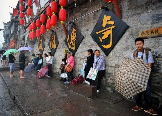 　4月29日上午11時20分，一些游客和古城當(dāng)?shù)氐木用穸阍谝粋€酒吧的屋檐下避雨。這些當(dāng)?shù)鼐用褚詾橛慰团恼罩\生，一場降雨讓他們的生意更加清淡。