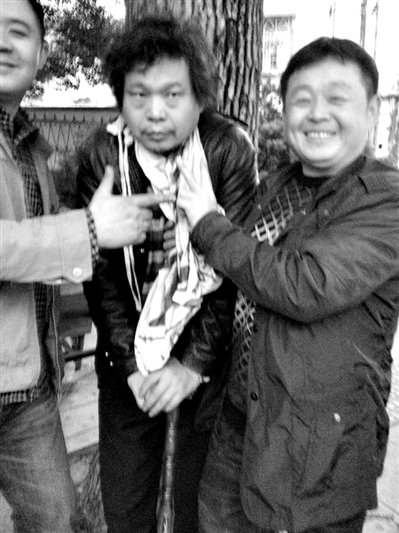 兩名接訪人員與患有癌癥的訪民段新德合影時，面帶笑容擺出勝利的手勢。