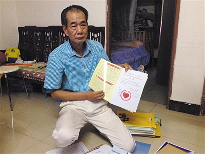 翻出一家網(wǎng)站贈(zèng)予的“中國(guó)好人”證書，區(qū)少坤單膝跪在地上，“你看，我是中國(guó)好人啊?！?范春旭 攝