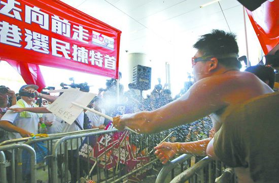 17日，在香港立法會外，一名反對政改的男子向支持派人群投擲標(biāo)牌。