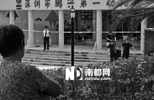 →7月19日，鵬興花園第一幼兒園門前，民警在現(xiàn)場(chǎng)進(jìn)行完勘查取證后，園長(zhǎng)和保安的尸體被運(yùn)走。南都記者 徐文閣 攝