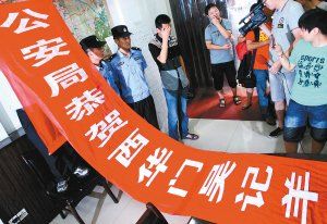 面對警方收繳的條幅，老板楊某也不好意思地用手遮擋臉