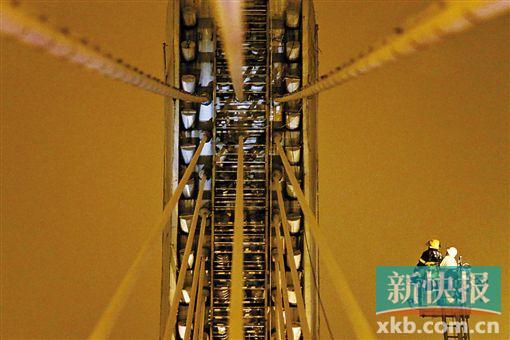 截至今日零時，男子仍未有下橋舉動。圖為公安和消防人員乘消防云梯在高空上和男子交談。