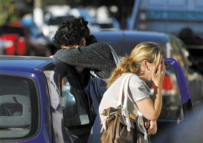 27日，遇難者親友在火災現(xiàn)場旁哭泣。