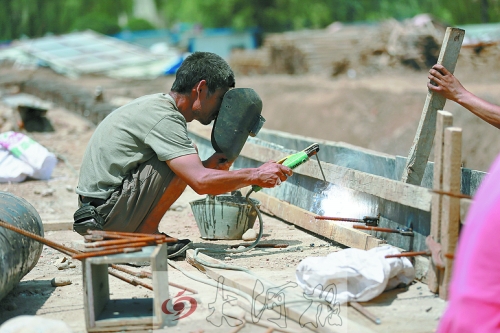 　正午陽光下，工地上的焊接工人還在認真工作。