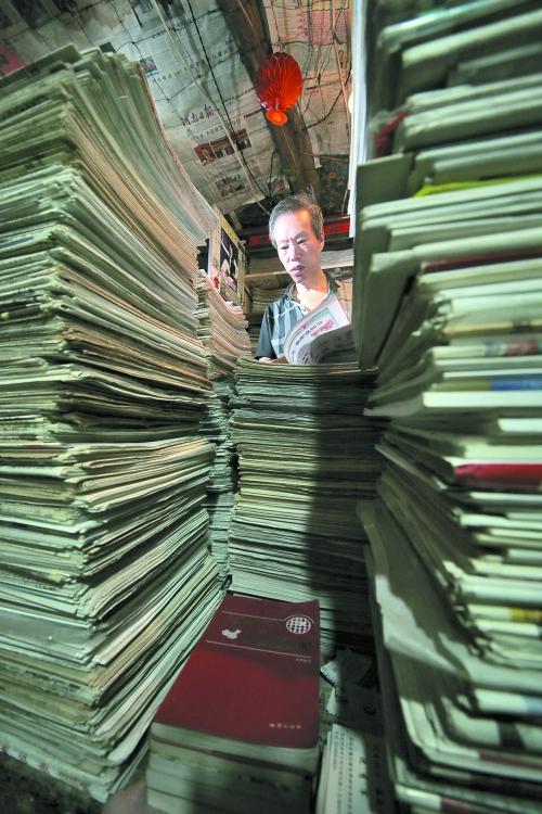 王曉民坐在寫字桌前，被報(bào)紙淹沒。