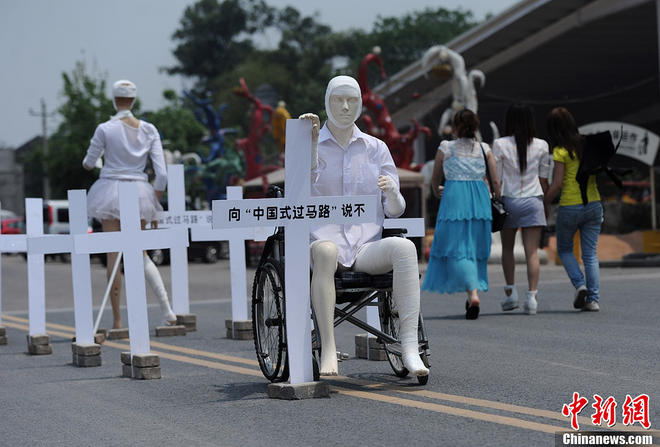4月16日，重慶市洋人街上擺放著兩個(gè)受了傷的塑料人像“模特”，旁邊十字架上寫(xiě)著向“中國(guó)式過(guò)馬路”說(shuō)不