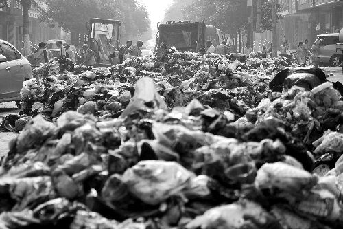 垃圾堆滿整個(gè)路口，環(huán)衛(wèi)工人們正在清理