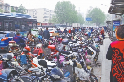 省人民醫(yī)院北門，路邊的公交站牌處停滿非機動車，上、下客只能在快車道上。