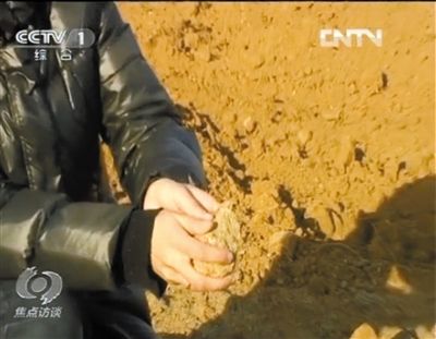 麻剛沙系麻剛石粉碎而成。記者找到一塊麻剛石，一捏就碎成粉末，硬度非常差。央視截圖