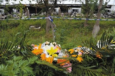 昨日，吉林省德惠市吉林寶源豐禽業(yè)有限公司燃燒事故現(xiàn)場警戒線外，遇難者家屬在路邊擺放了花圈祭奠逝去的親人。吳江 攝