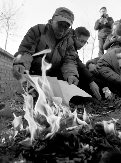 李三仁在兒子墳前焚燒再審無罪判決文書的復印件。新華社發(fā)