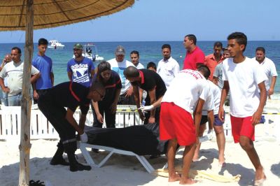 6月26日，在突尼斯蘇塞，救生員和醫(yī)務人員在發(fā)生襲擊事件的海灘運送一名死者的遺體。新華社發(fā)