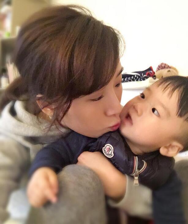 照片中李念狂吻兒子，小寶貝自顧自地玩著。