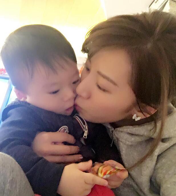 照片中李念狂吻兒子，小寶貝自顧自地玩著。