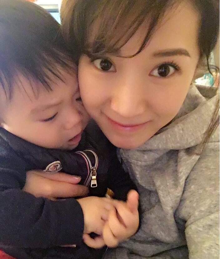 照片中李念狂吻兒子，小寶貝自顧自地玩著。