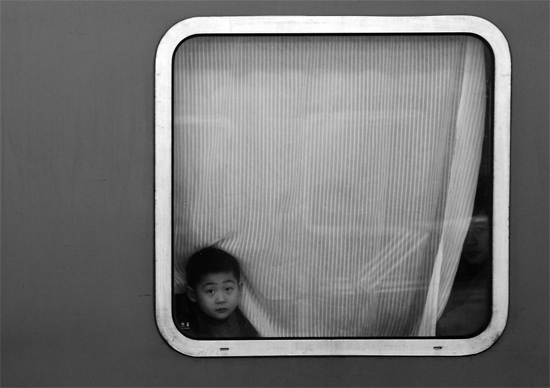 一個(gè)孩子把頭伸向窗外，他想再看送別的親人一眼