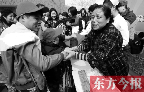 昨日，鄭大四附院的大樓前，“面人鄭”鄭玉芬（右）向前來捐款的殘疾人表示感謝