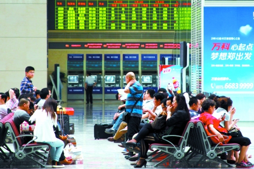 候車大廳溫度很高，一名乘客一手扇風、一手擦汗