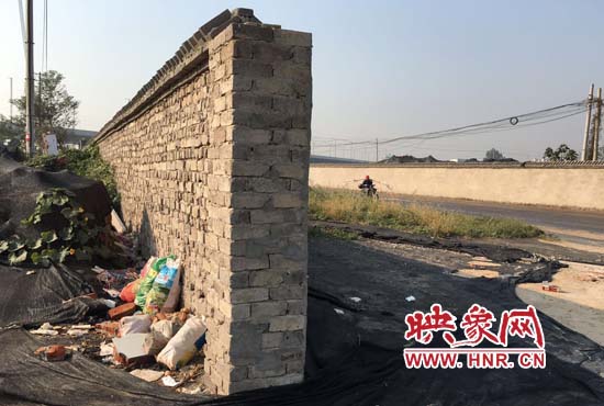 一墻之隔，一邊是道路，一邊是垃圾和荒草，市民質(zhì)疑其為遮羞墻。