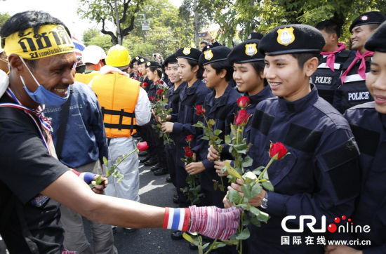 2013年12月03日,曼谷總理府與曼谷警署允許反政府示威民眾進(jìn)入,雙方進(jìn)入暫時(shí)“停戰(zhàn)”狀態(tài)迎接泰王生日。曼谷警察總署,女警們手持鮮花送給反政府示威民眾。圖片來源:Manish Swarup/東方IC