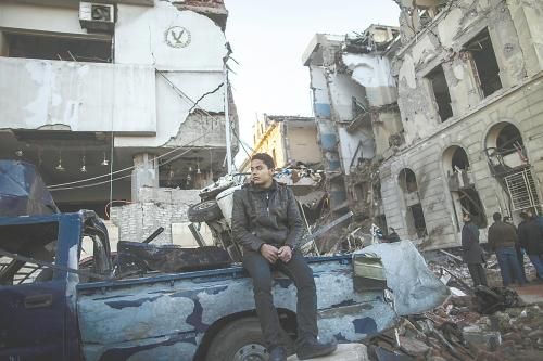 埃及曼蘇拉市警察局24日遭汽車炸彈襲擊，被疑是穆兄會(huì)的報(bào)復(fù)。圖為一名男子在被炸毀的警察局前。