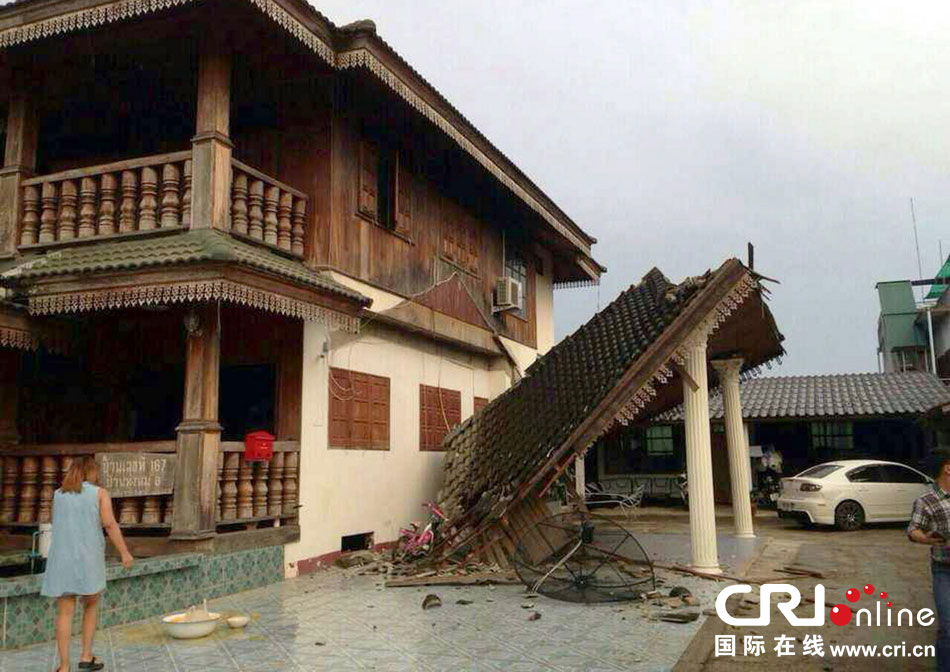 當?shù)貢r間2014年5月5日，泰國清萊，一名婦女看著受損的房屋。 圖片來源：東方IC