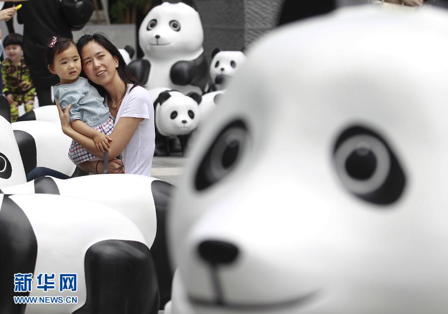 6月2日，一位家長帶著孩子在上海街頭和大熊貓模型合影。