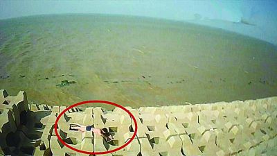 孫正龍游上岸，趴在海邊精疲力盡。