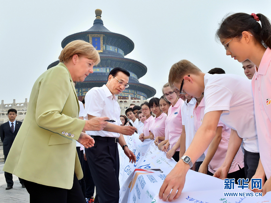 李克強(qiáng)同默克爾在紀(jì)念橫幅上簽名。