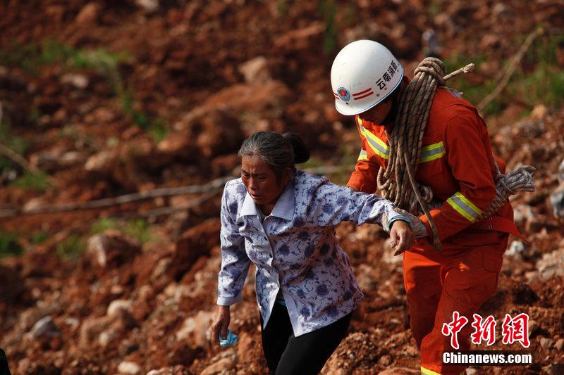 一位消防戰(zhàn)士將一位失去親人的老人扶離滑坡點。