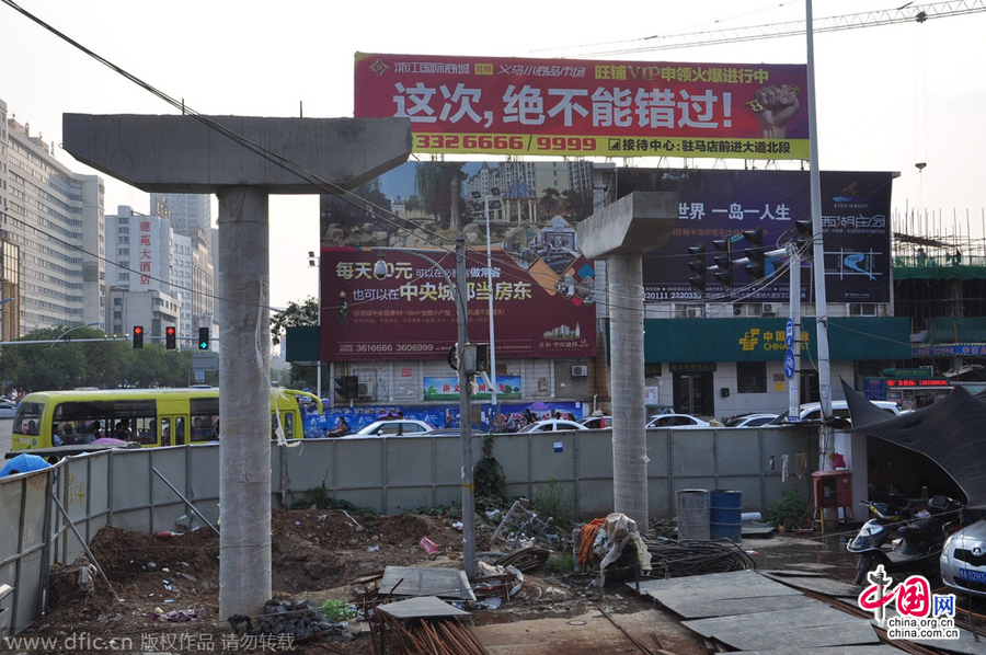 過街天橋一側(cè)的橋樁早已打好,可是對面的郵政銀行網(wǎng)點依舊在照常營業(yè)。