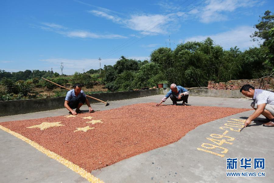 村民馬玉明（左一）用豐收的高粱和玉米在院壩里擺國旗為祖國慶生。