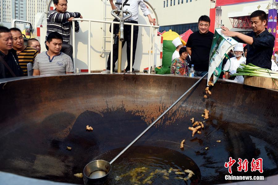 工作人員向大鍋內(nèi)加入油和姜等烹飪調(diào)料。 圖片來源：CFP視覺中國