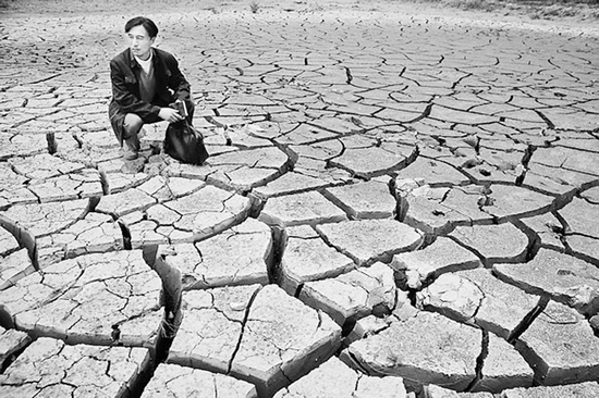 蹲在干涸的田地里，焦裕祿為饑餓的百姓揪心不已 《焦裕祿》劇照